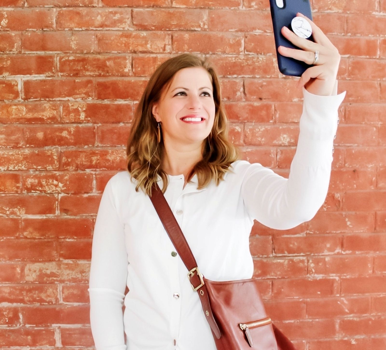 Tracy Smith, Founder of Kitchen Table CEOs taking a selfie and demonstrating how to take a picture of yourself for social media.