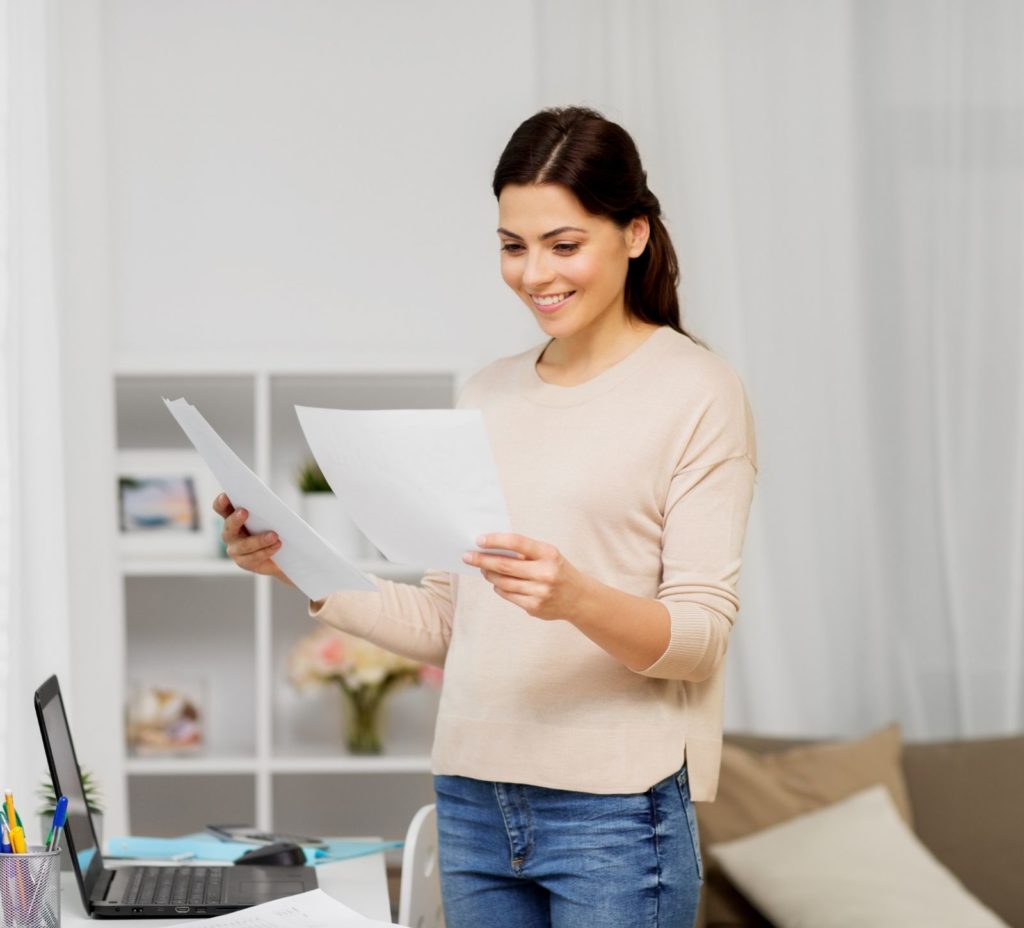 woman entrepreneur standing by laptop reviewing taxes
