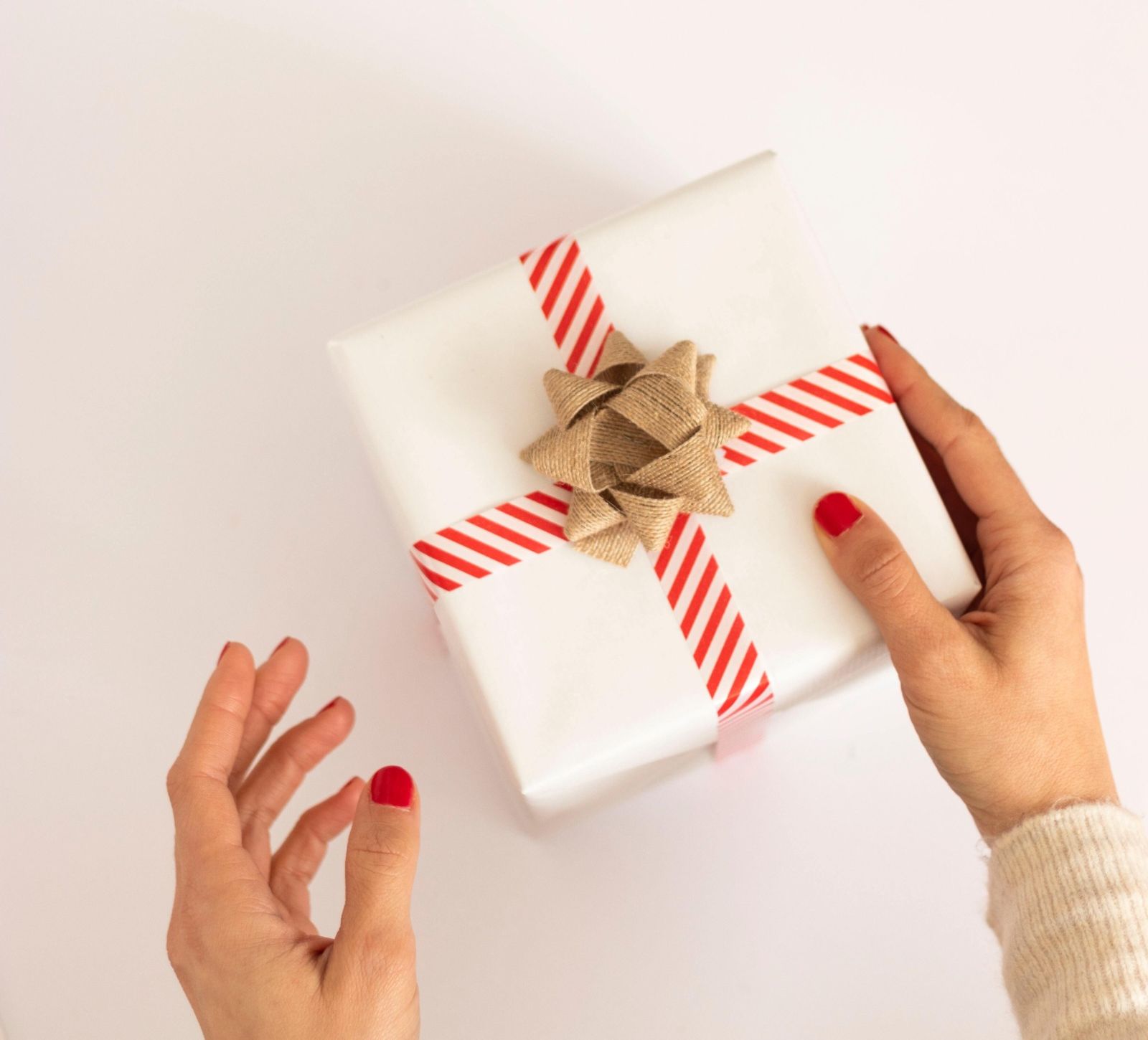 Kitchen Table CEOS Blog Holiday Gift Giving Guide ~a la my clients - hand holding a small gift box with red & white ribbon with a bow.